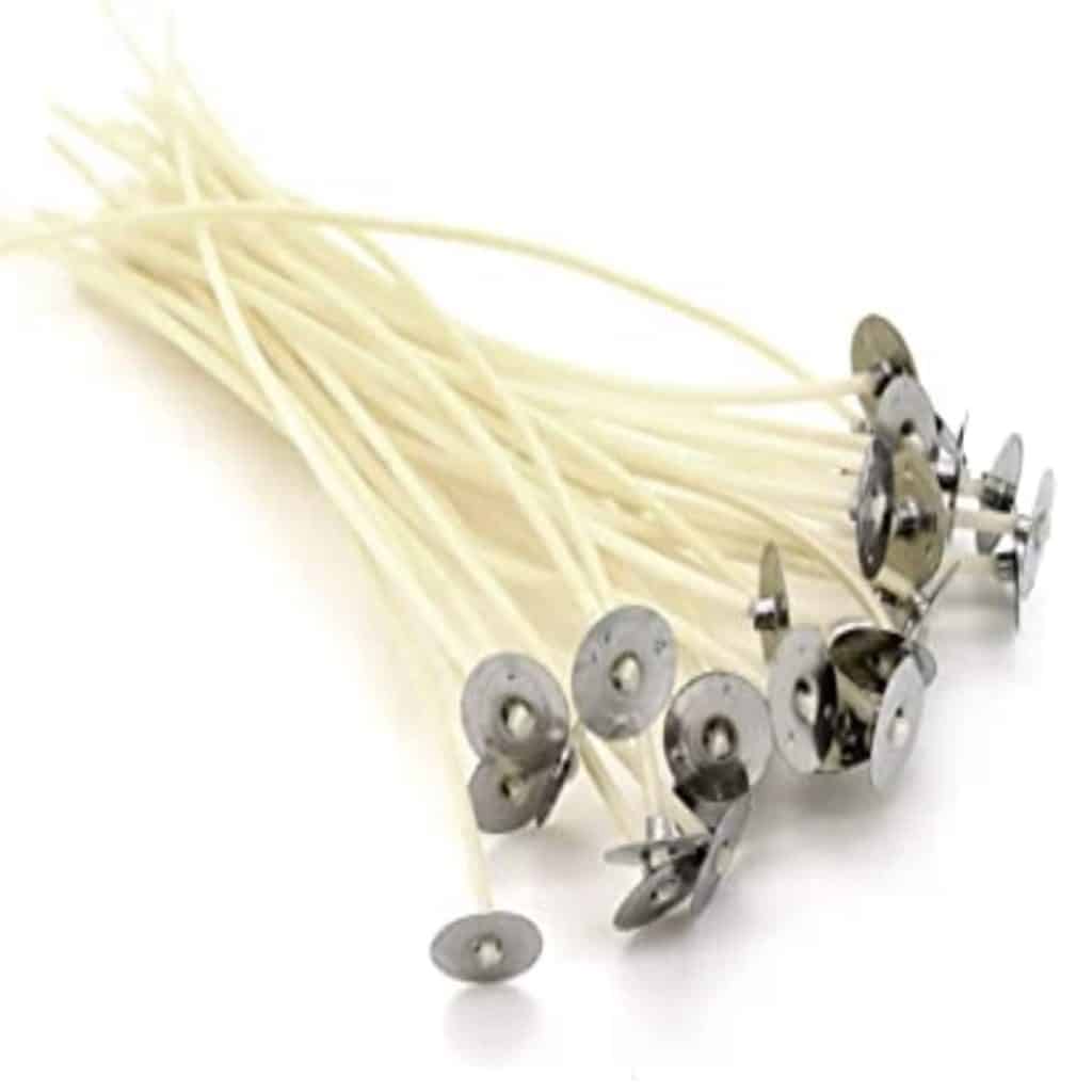 A bundle of pre-waxed white candle wicks with metal tabs at the ends, evocative of candles adorned with delicate dried flowers, gracefully arranged on a white background.